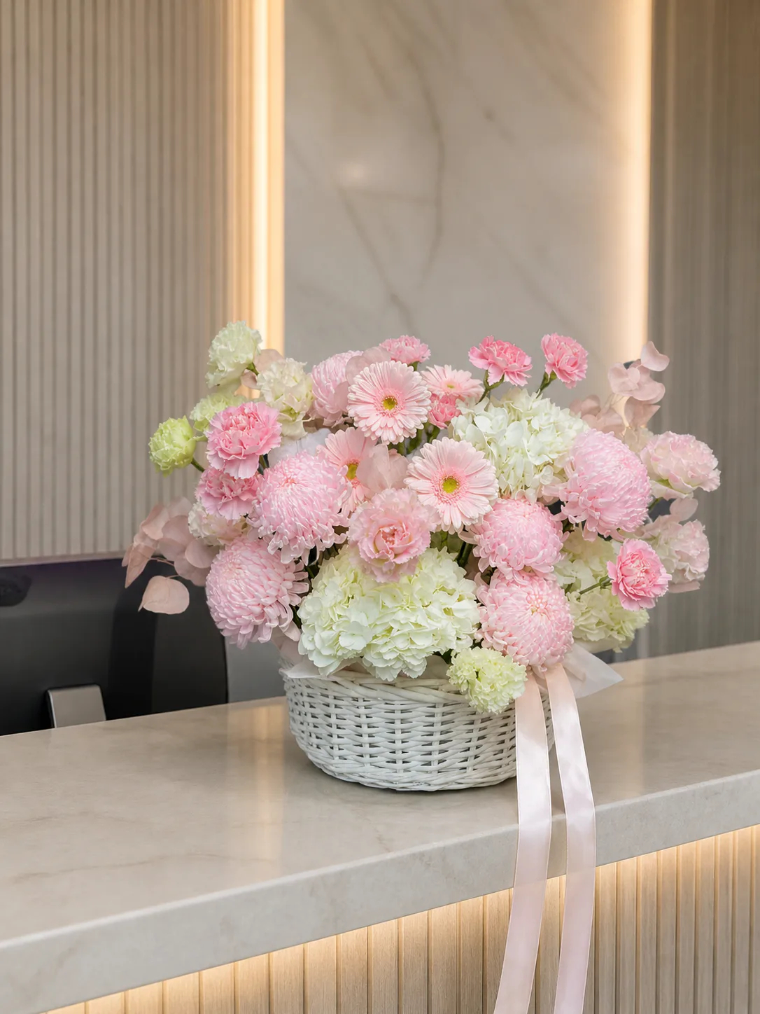 pastel pink and white floral basket on a corporate reception counter by Boston Flowers