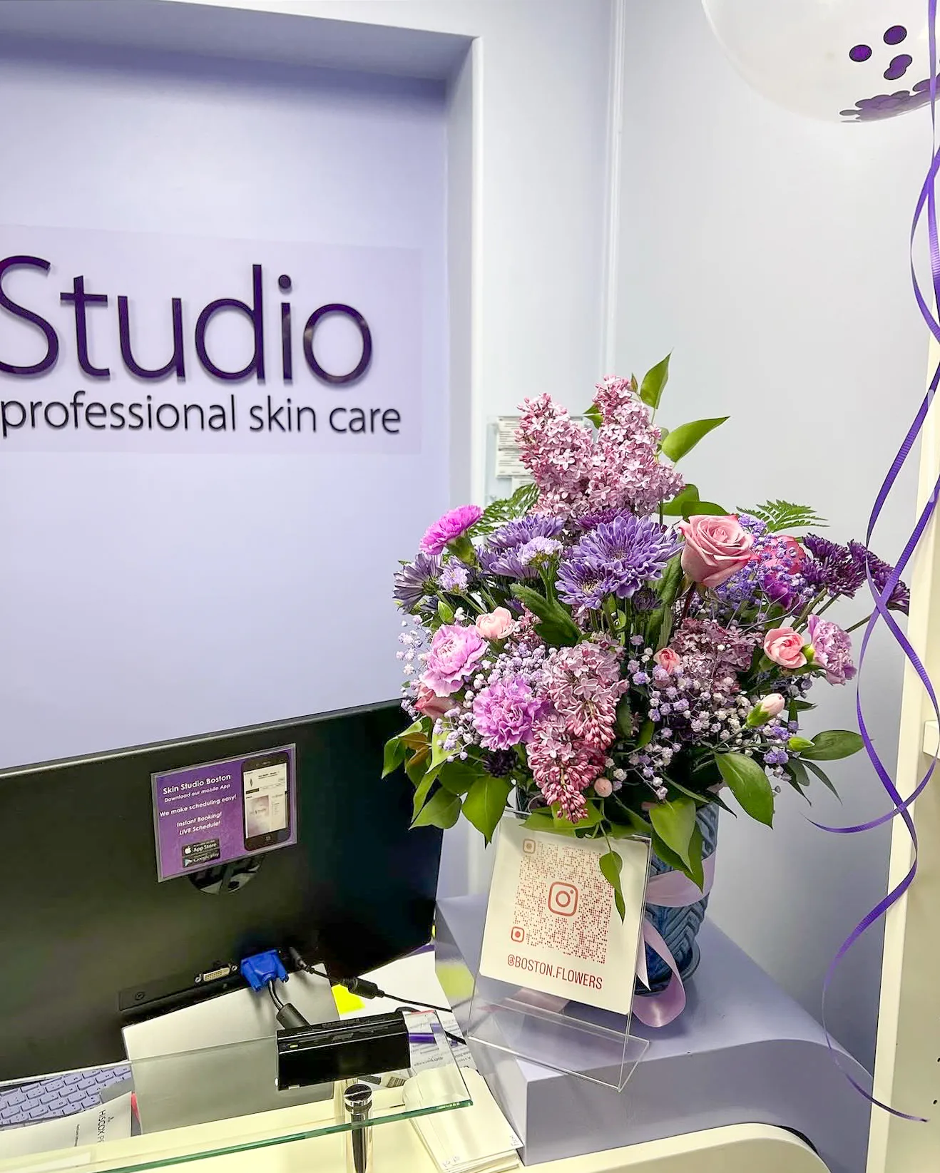Purple and pink floral arrangement displayed at a professional skin care studio reception