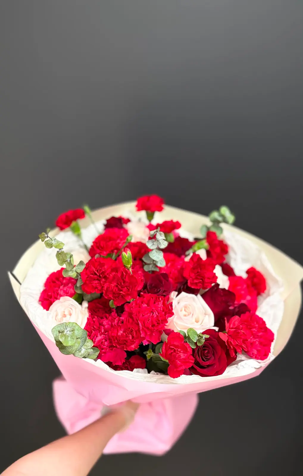 Close-up of Orleans Opera bouquet with red carnations, red and blush roses, and eucalyptus