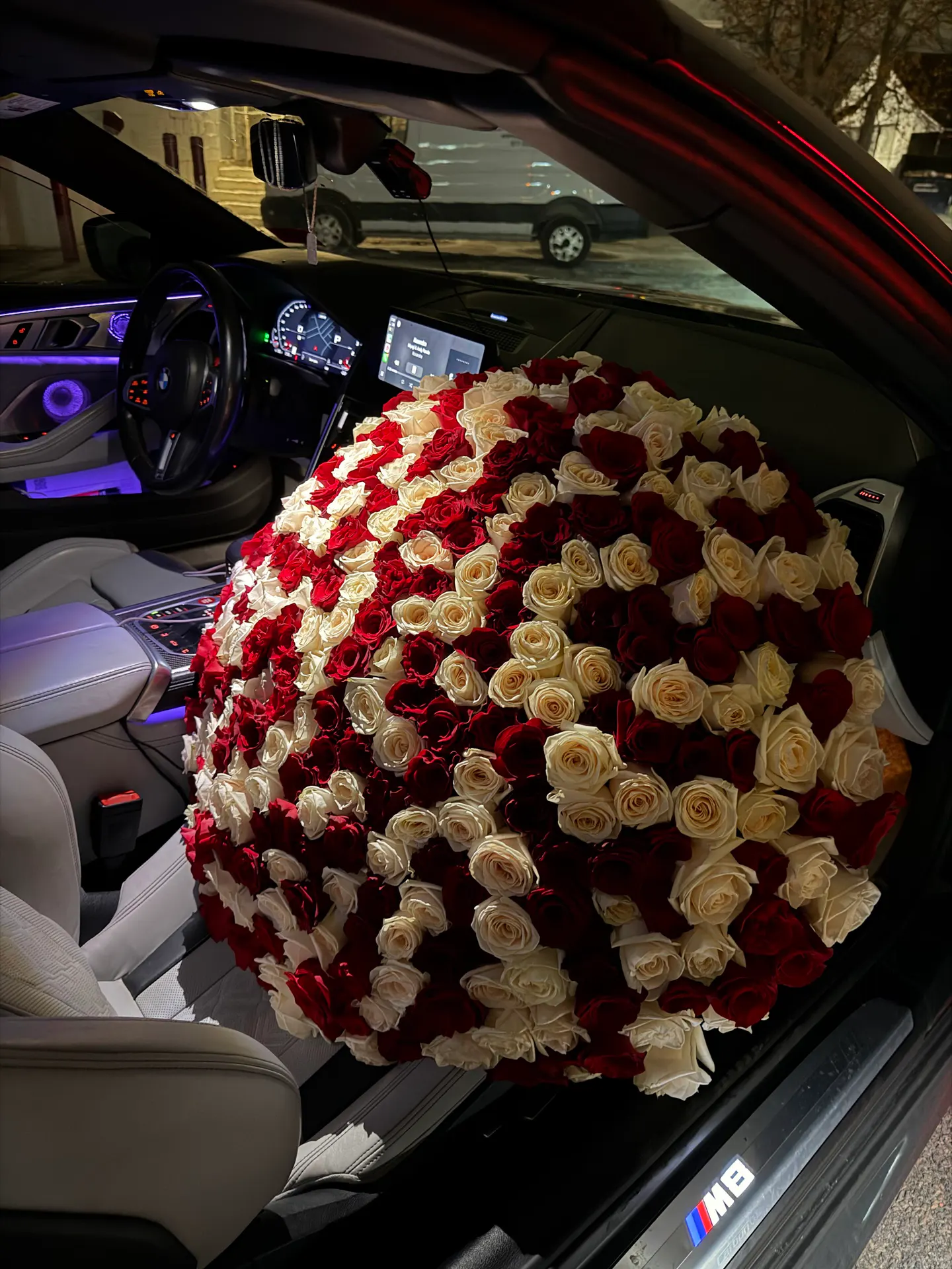 large red and white roses arrangement placed inside a car for delivery in Boston
