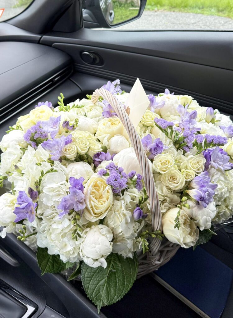 White peonies, roses, hydrangeas and lavender freesia in a woven basket