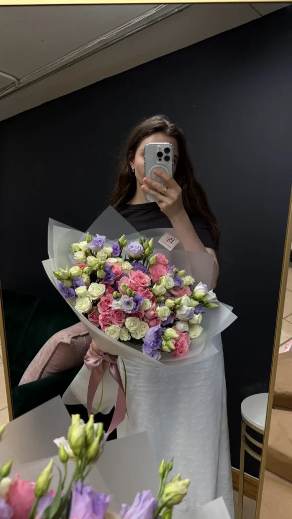 Woman holding a pink, white, and lavender bouquet of roses and eustoma