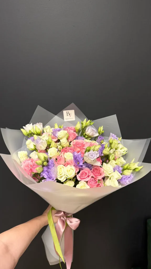 Close-up of pink roses with white and lavender eustoma in gray wrapping