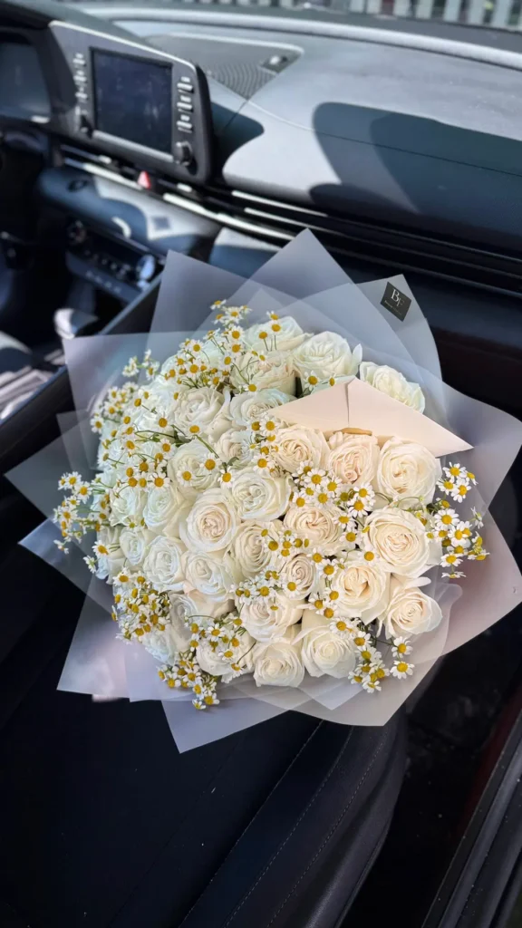 Large white rose and chamomile bouquet displayed inside a car