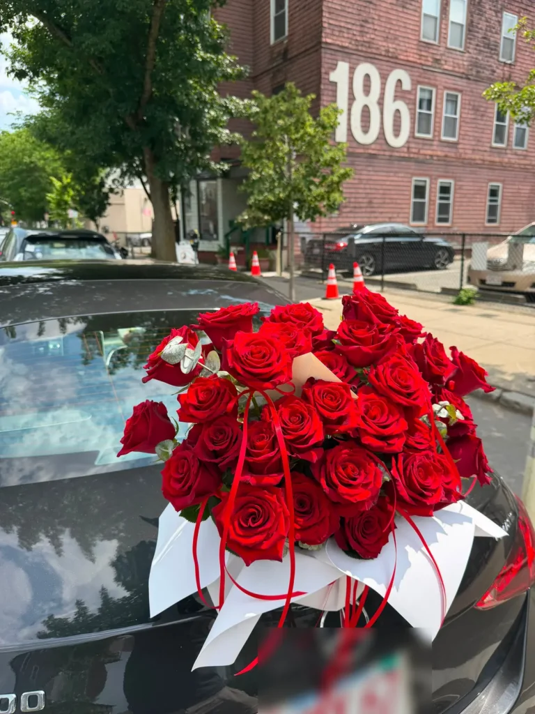 Commonwealth Crimson deluxe bouquet of deep red roses in white wrap with trailing red satin ribbons, view 3