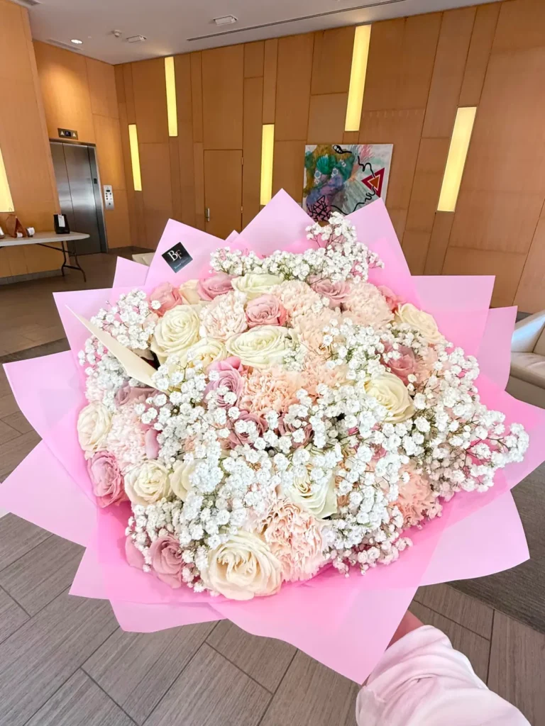 Newbury Street Blush bouquet of ivory and dusty pink roses, blush carnations and baby's breath in soft pink wrap