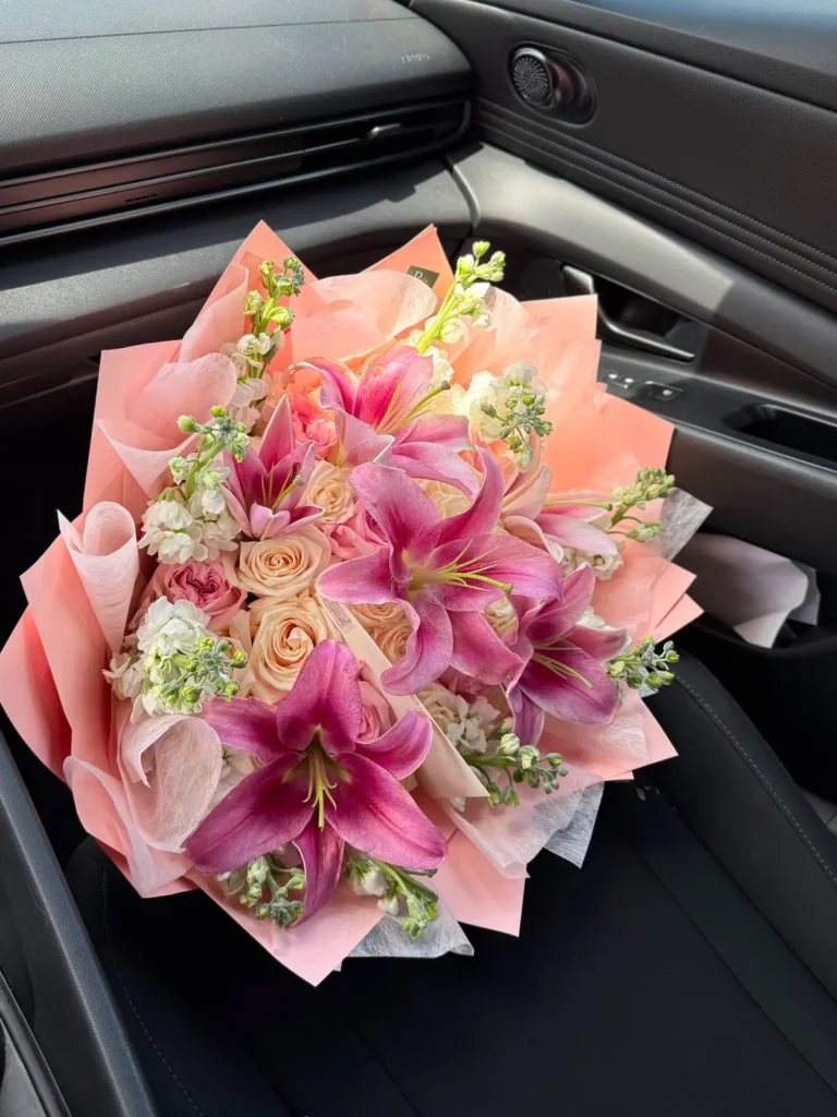South End Stargazer bouquet of magenta Stargazer lilies, champagne roses and white stock in soft peach wrap, view 3